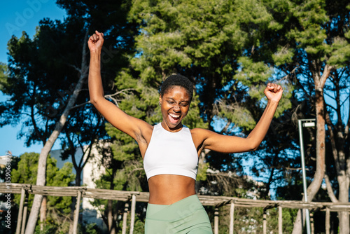 Wallpaper Mural Happy athlete celebrating victory in a park raising her arms Torontodigital.ca