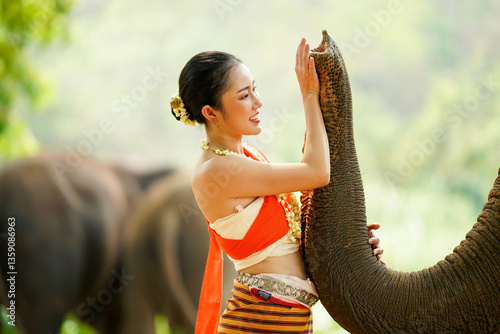 Canvastavla Closeup portrait of beautiful Thai woman in the Thai northern traditional dress photo shoot and touching with trunk of Asian elephant on blurred background