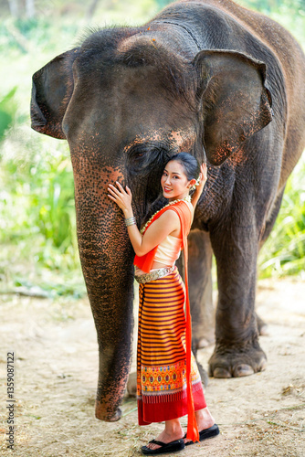 Portrait of Beautiful rural Thai woman wear Thai northern traditional dress for photo shoot with Asian elephant on blurred background.