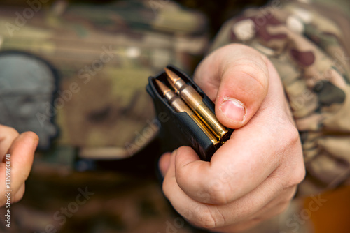 Firearms, AK magazine with 7.62x39mm cartridges in a man's hand. photo
