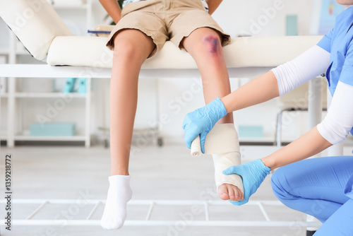 Photography Female doctor bandaging little boy's injured leg in clinic