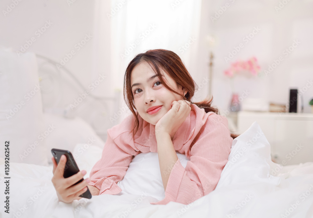 Asian woman using mobile phone to play social media on bed, smiling happily at home Asian woman using mobile phone to play social media on bed, smiling happily at home