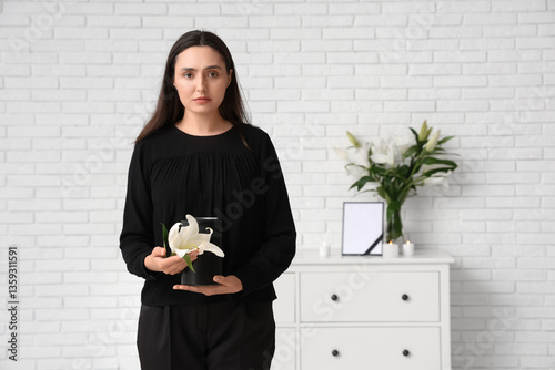 Young woman with mortuary urn and lily flower in room