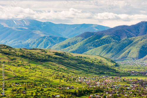 Obraz na płótnie mountainous countryside landscape with kolochava village in the valley. cloudy weather. rural fields and meadows on the forested slopes of a hill. rolling alpine scenery in spring w salonie