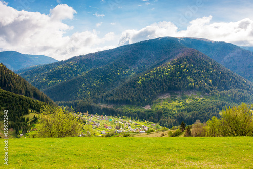 Obraz na płótnie mountainous countryside landscape with synevyr village in the valley. amazing carpathian adventure. cloudy weather. rural fields and meadows on the forested slopes of a hill. rolling scenery in spring w salonie