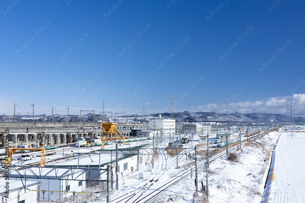 Obraz premium 冬の青空と積雪をバックに走る東北本線（利府）