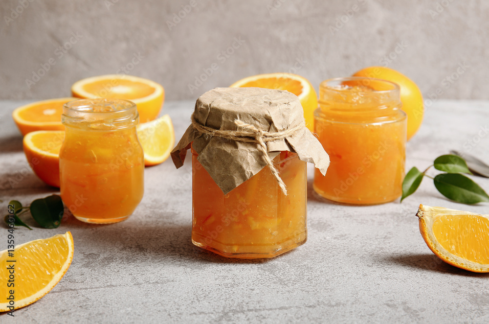 Jars of sweet orange jam and fruits on grey background Jars of sweet orange jam and fruits on grey background