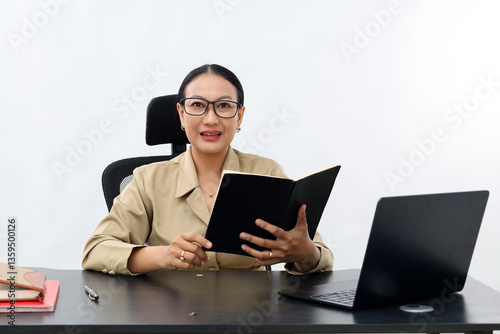 Attractive surprised young Asian civil servant woman in formal working at his desk in the white office room while reading book