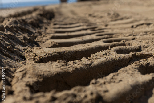 Close-up of excavator tracks on the sandy beach and the excavator behind  in a blur . Work for the beginning of the tourist season. Mediterranean,  Turkey