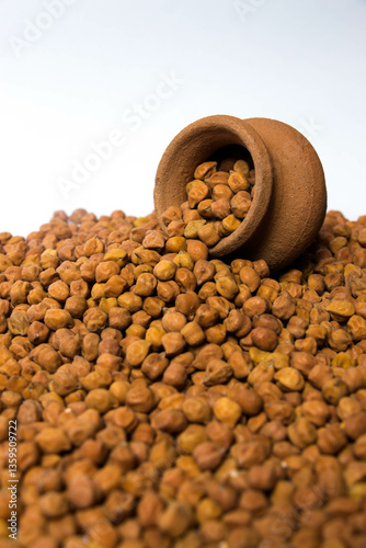 Fototapeta Vertical shot of Organic Brown Chickpeas in a earthen clay pot Isolated on a white background
