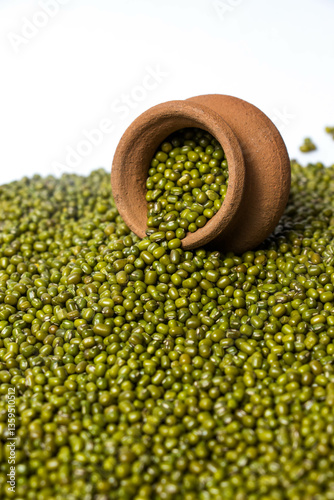 Fototapeta Vertical shot of Green Moong Dal beans in a earthen clay pot Isolated on a white background