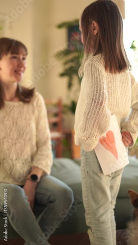 Girl holds a card with a picture of a heart and gives it to her mother on Mother's Day.