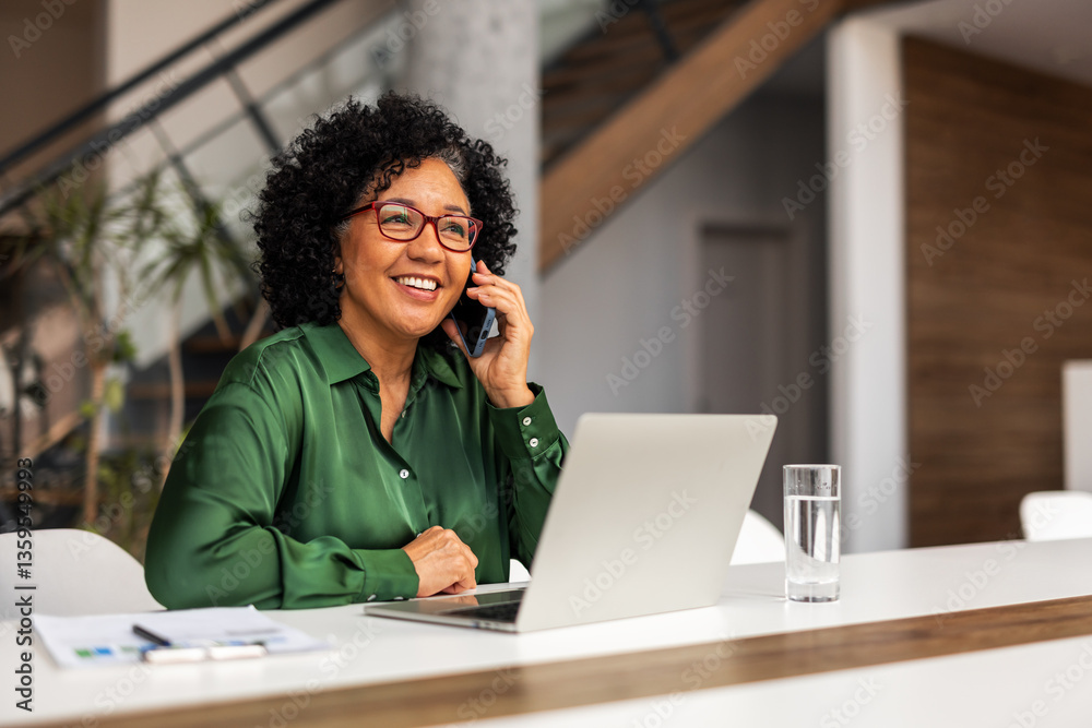 Professional Woman Working Remotely Using Laptop and Phone in Modern Office