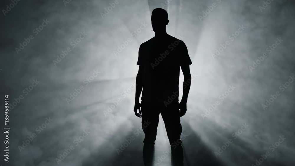 Silhouette of a man standing in dramatic backlight with rays piercing through fog in a mysterious environment. Concept of inner strength and psychological depth Silhouette of a man standing in dramatic backlight with rays piercing through fog in a mysterious environment. Concept of inner strength and psychological depth