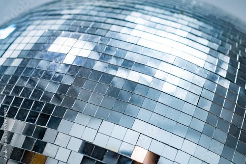 Close-up of shiny disco ball reflecting light with silver mirror tiles