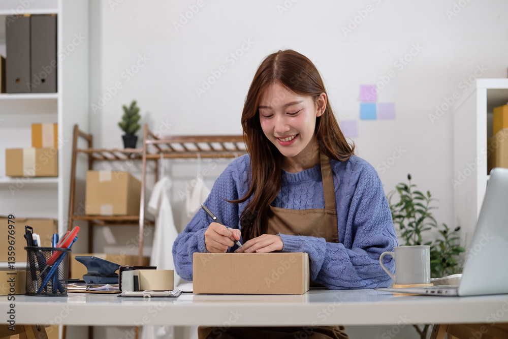 Young female online seller preparing package and writing addressee details on cardboard box. Young female online seller preparing package and writing addressee details on cardboard box.