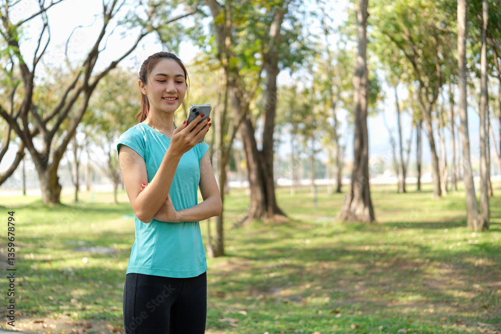 Smiling woman checking her smartphone while taking a break in a scenic park during outdoor workout. Smiling woman checking her smartphone while taking a break in a scenic park during outdoor workout.