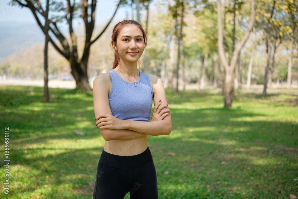 Young sportswoman standing with her arms crossed in a lush green park. Self-confidence healthy lifestyle and wellness concept. Young sportswoman standing with her arms crossed in a lush green park. Self-confidence healthy lifestyle and wellness concept.