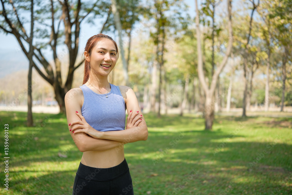 Active and confident sporty woman standing with her arms crossed in a lush green park. Self-confidence healthy lifestyle and wellness concept. Active and confident sporty woman standing with her arms crossed in a lush green park. Self-confidence healthy lifestyle and wellness concept.