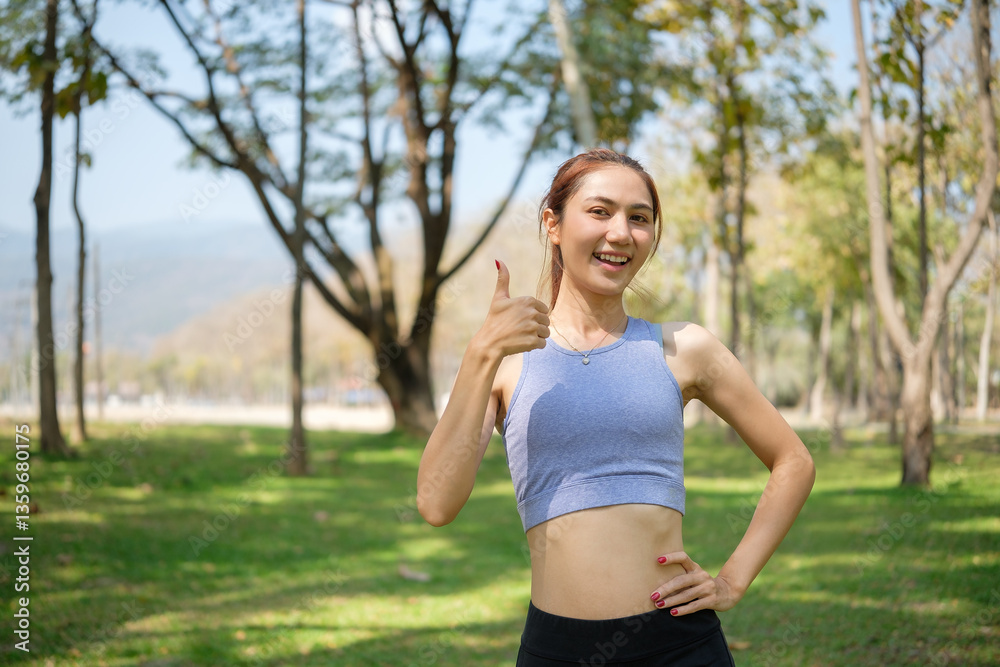 Smiling young sportswoman giving thumbs up after successful workout session in a beautiful park. Fitness, wellness, and a healthy lifestyle concept. Smiling young sportswoman giving thumbs up after successful workout session in a beautiful park. Fitness, wellness, and a healthy lifestyle concept.