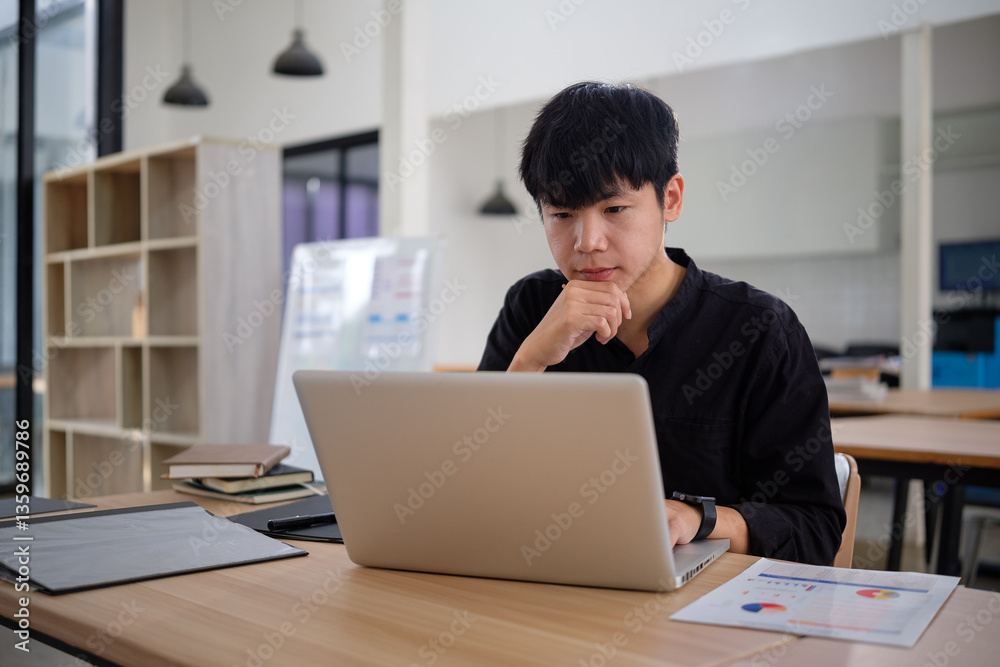 Thoughtful young businessman working on a laptop, analyzing data. Thoughtful young businessman working on a laptop, analyzing data.
