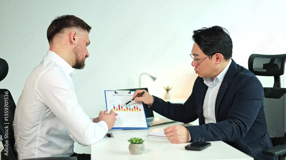 Two businessmen, one Korean, analyze a business chart in a modern office. They discuss strategy and financial data for better decision-making. Two businessmen, one Korean, analyze a business chart in a modern office. They discuss strategy and financial data for better decision-making.