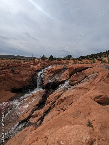 Gunlock Falls Cascading Over Red Rocks in a Stunning Desert Landscape. photo