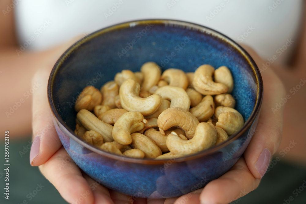 Cashew nuts. Close-up of female hands holding a bowl full of cashew nuts.