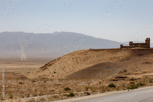 Cuadro en lienzo Dusty landscape and abandoned structure in the Afghan desert under a clear blue