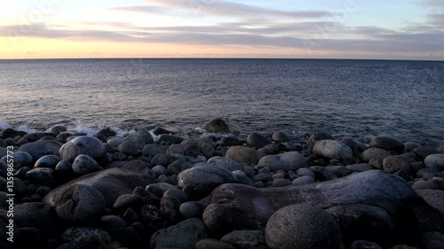 Dragon Egg beach rocks in the waves of the Barents Sea on a March evening. Teriberka, Murmansk region, Russia