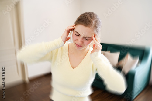 Female having dizziness holding hands on forehead at home. Tired woman with closed eyes feeling dizzy standing in the living room. Vertigo, health problems, low blood pressure, vestibular, brain pain.
