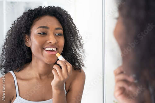 One black woman using lipstick in the bathroom