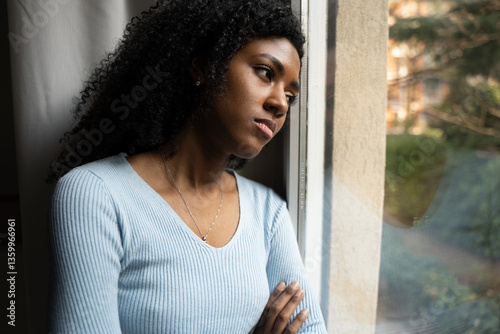 A black woman very sad thinking in front of window photo