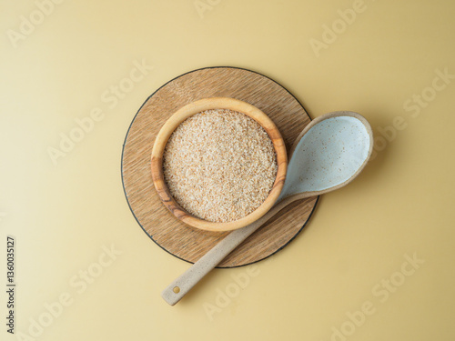 Psyllium husk in the plate with spoon on yellow background.