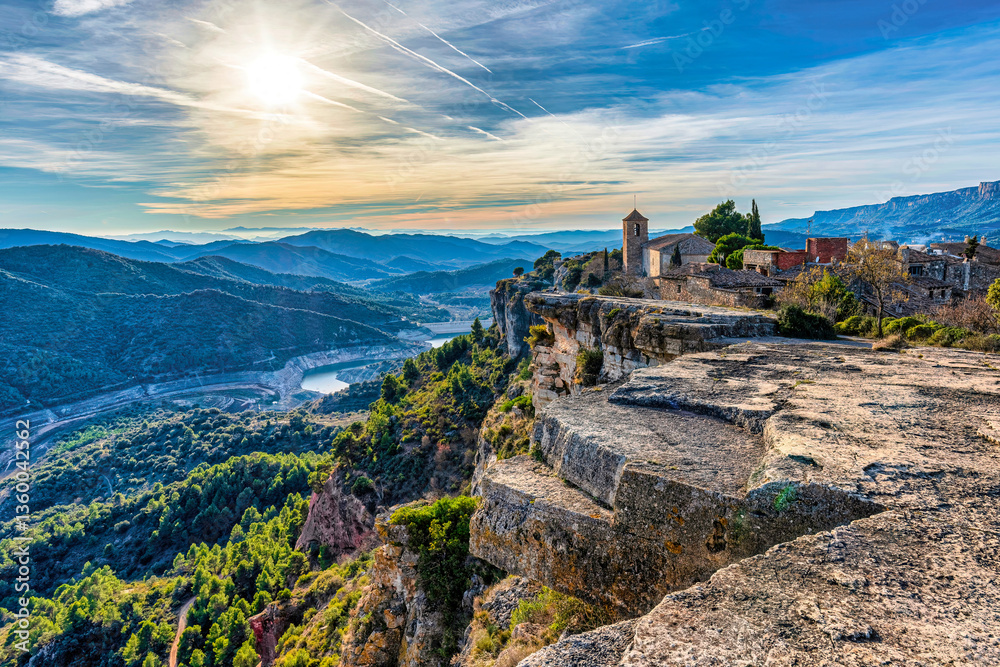Fototapeta premium Aerial view of Siurana, Catalonia, with church and mountains. A stunning view of Siurana, Spain, showcasing its church, dramatic cliffs, and sunset.
