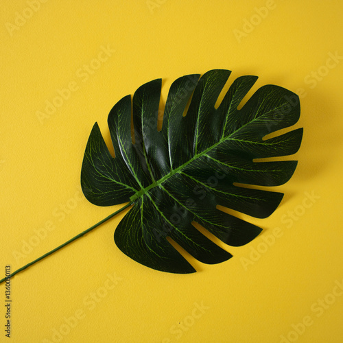 Green palm leaf as decoration on a yellow wall