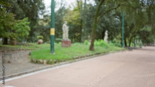 Wallpaper Mural Blurred view of a serene park street in la spezia, italy, with statues and lush greenery creating a tranquil urban atmosphere. Torontodigital.ca