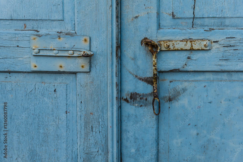 Weathered blue wooden door with rusty hardware and chain lock in a rustic setting