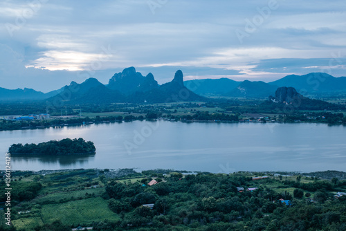 Phusab Lek : LOPBURI, THAILAND, Tranquil Waterscape: A serene panorama unfolds, featuring a tranquil lake embraced by rolling hills and under a gentle, clouded sky. 