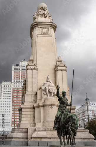 Bronze statues of don quixote and sancho panza at the foot of a stone monument dedicated to miguel de cervantes