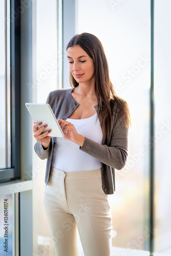 Attractive brunette haired businesswoman standing in a modern office and using her digital tablet for work Free Download Attractive brunette haired businesswoman standing in a modern office and using her digital tablet for work - GFXLoad