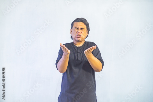 Obraz na płótnie Asian Muslim men pointing to the copy space beside her, isolated by white background. Ramadan and Eid Mubarak concept. w salonie