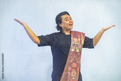 Obraz na płótnie Asian Muslim men pointing to the copy space beside her, isolated by white background. Ramadan and Eid Mubarak concept. w salonie