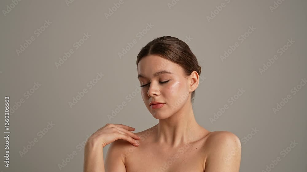 Young woman posing at camera playfully smiling touching smooth skin, isolated on white background. Slow motion.