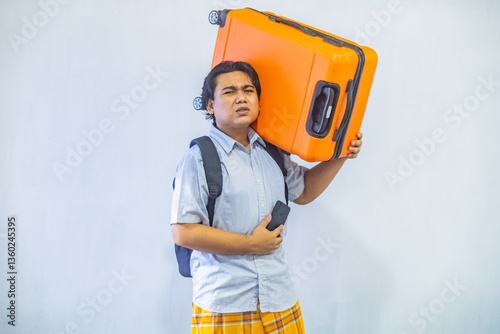 Portrait Asian muslim man carrying suitcase while holding mobile phone with copy space inside. Concept Going home for Eid Mubarak. Isolated image on white background
