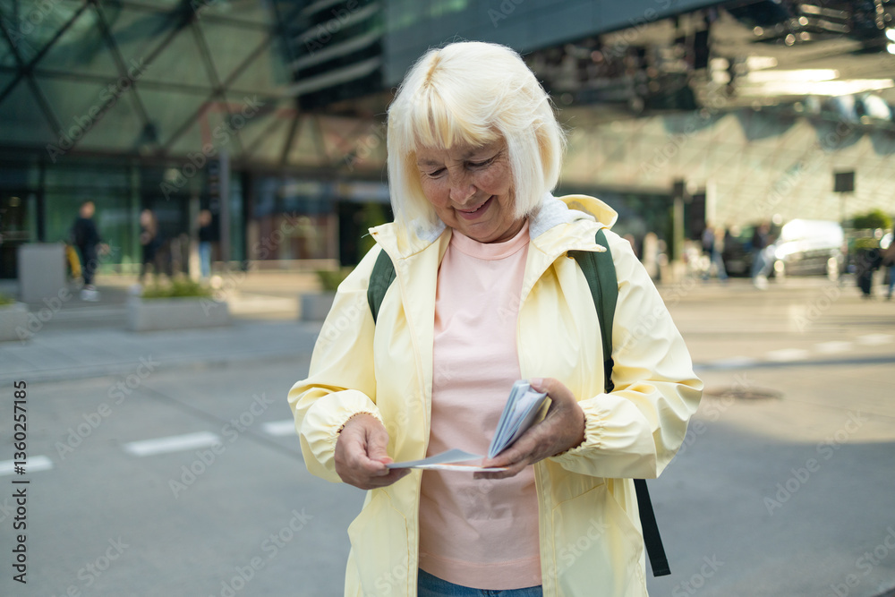 Senior female tourist in airport hold backpack passport ticket schedule to check flight departure gate. Travel and tourism concept, people with backpack on shoulders. High quality photo
