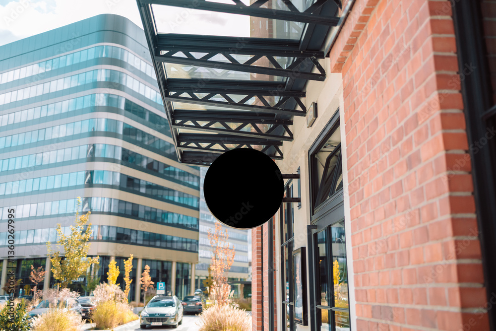 a close-up view of a modern building facade with a store sign hanging outside. The sign is framed by a sleek metal canopy, set against contemporary office buildings