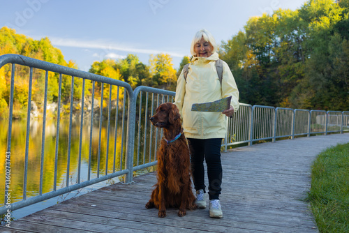An elderly woman with travel map and dog in autumn nature. High quality photo
