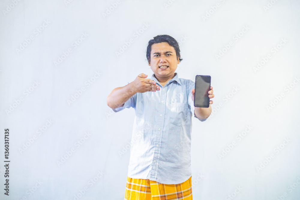 Portrait of surprised young Asian Muslim men showing blank screen on phone with copy space inside. Ramadan and Eid Mubarak concept