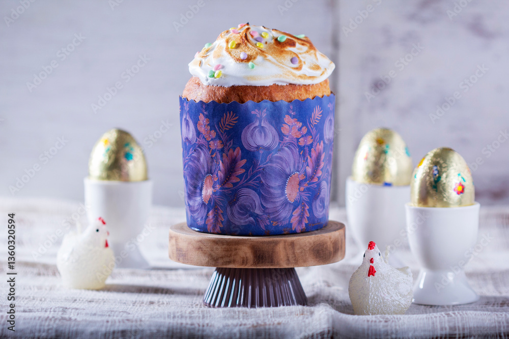 Easter cake, chocolate eggs in gold foil and chicken-shaped candles on a light background.